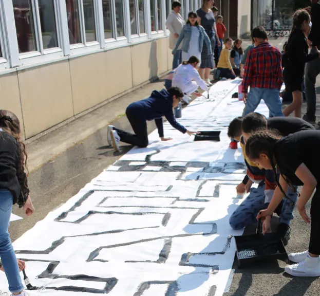 Rouleau de papier couvert de dessins, déroulé devant l’école